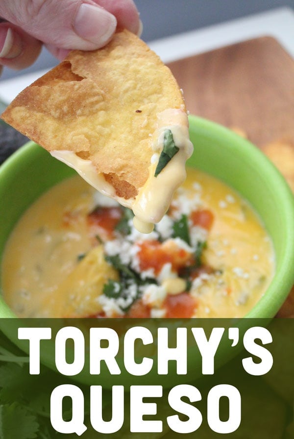 A tortilla Lifting up some of the queso dip.