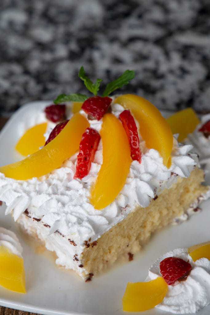 tres leches cake topped with peach slices and strawberries