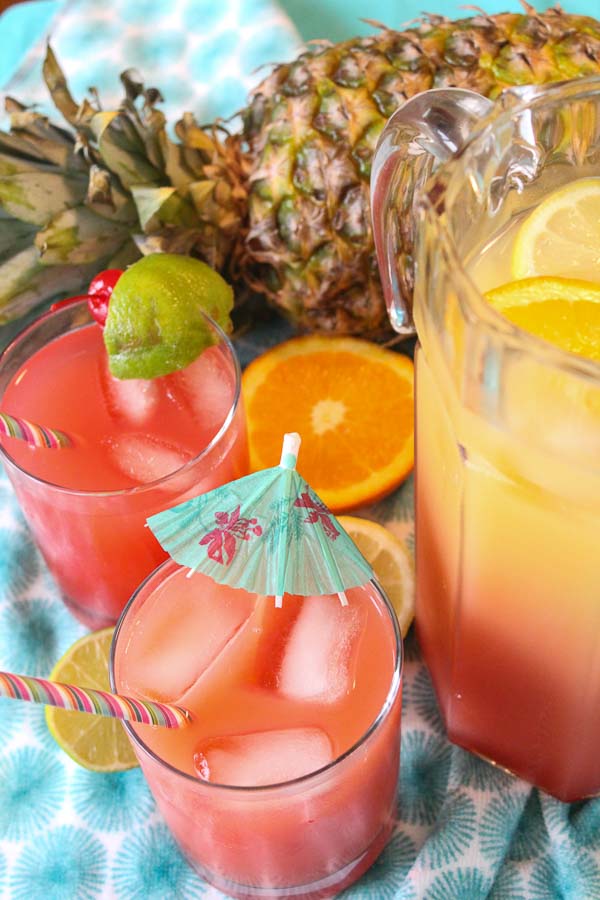 two glasses of rum punch cocktail with ice and lime garnish