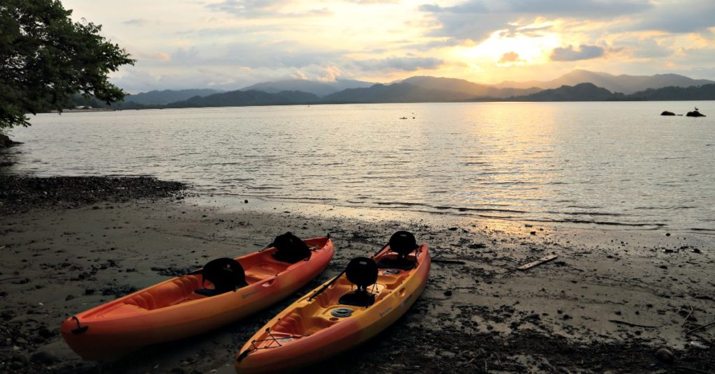 Two orange kayaks on bay in Costa Rica at sunset.