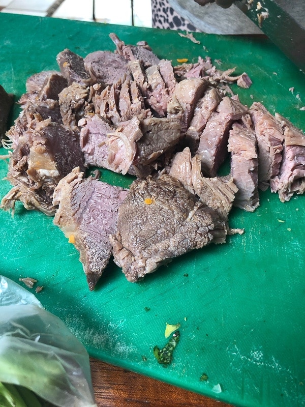 Sliced pork for Costa Rican Tamales on a green cutting board.