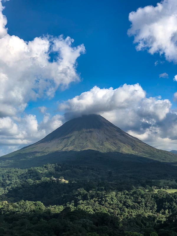 view of arenal volcano with blue sky and clouds costa rica