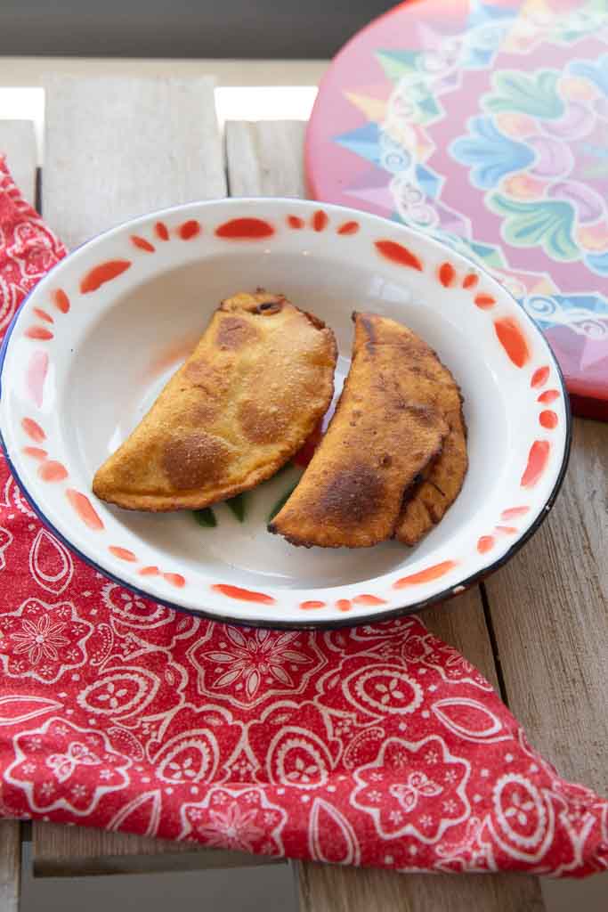 Two beef empanadas on a ceramic platter.