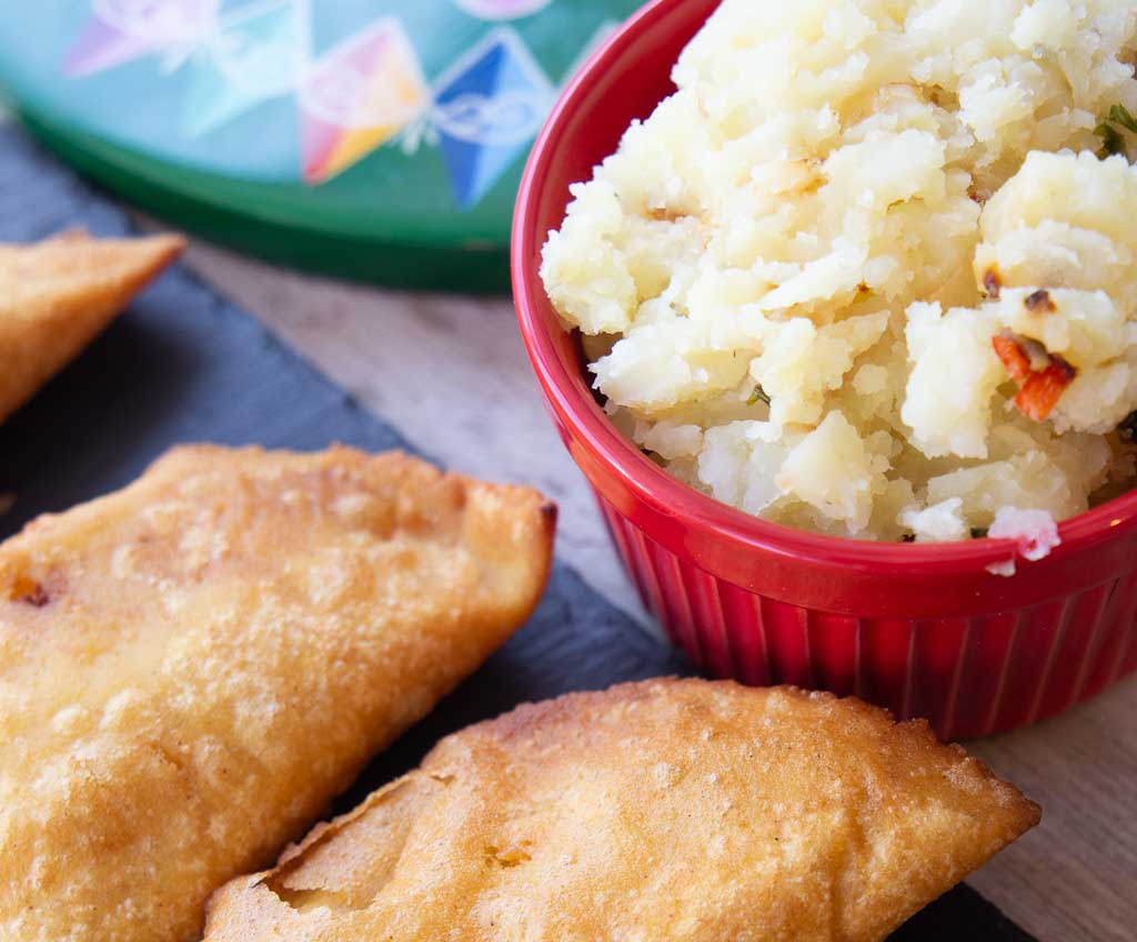 Costa Rican potato empanadas and filling in a red bowl.