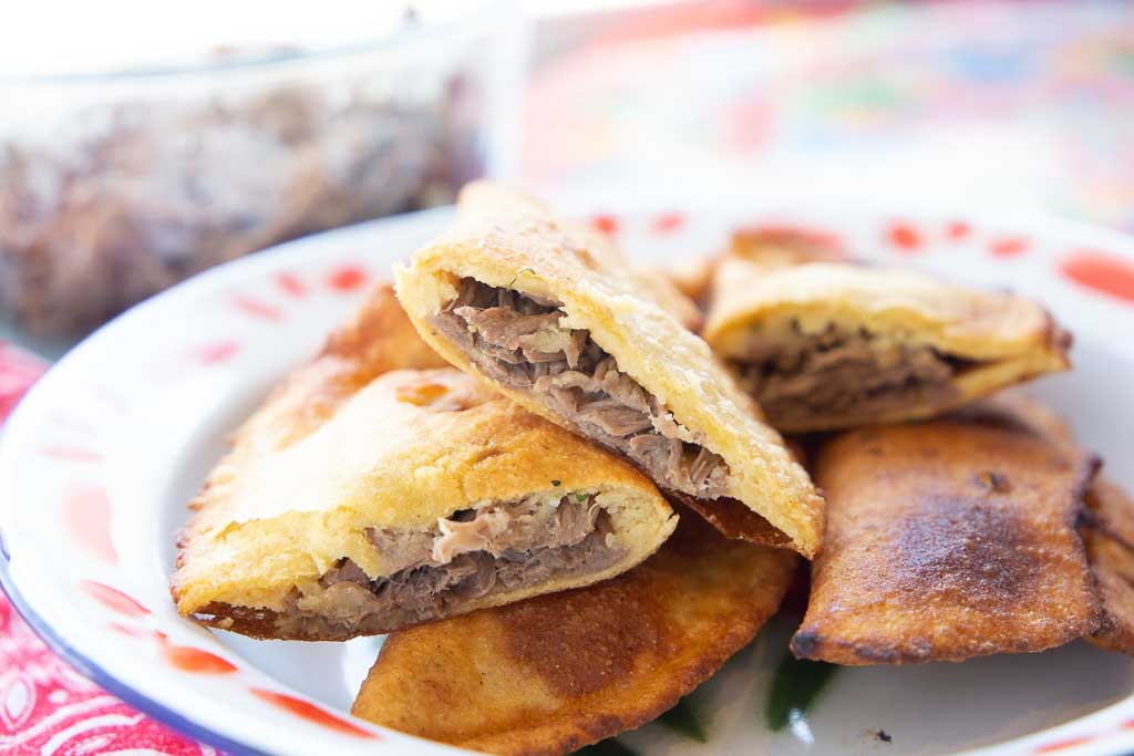 Close-up of beef empanadas cut into halves.