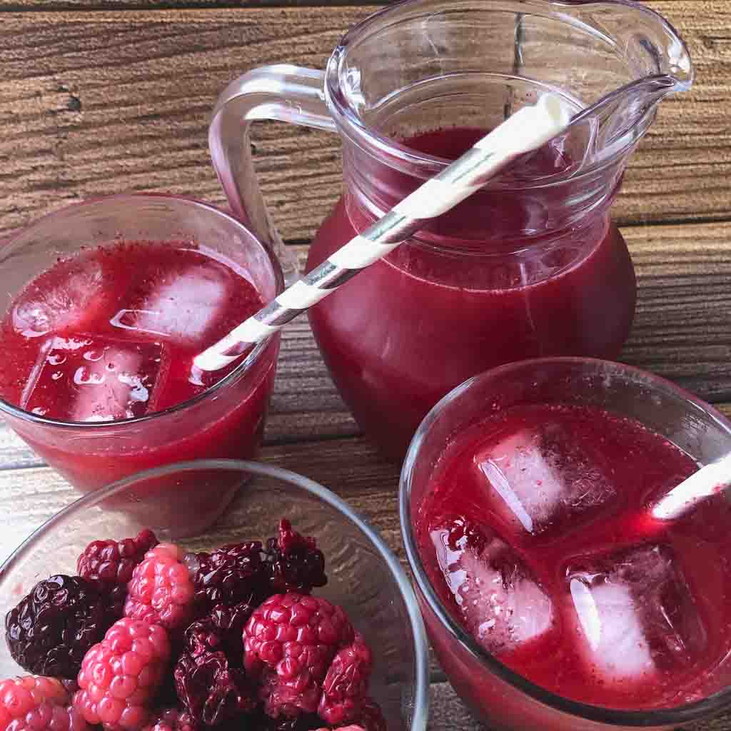 Glasses of fresh blackberry juice with pinstriped straws.