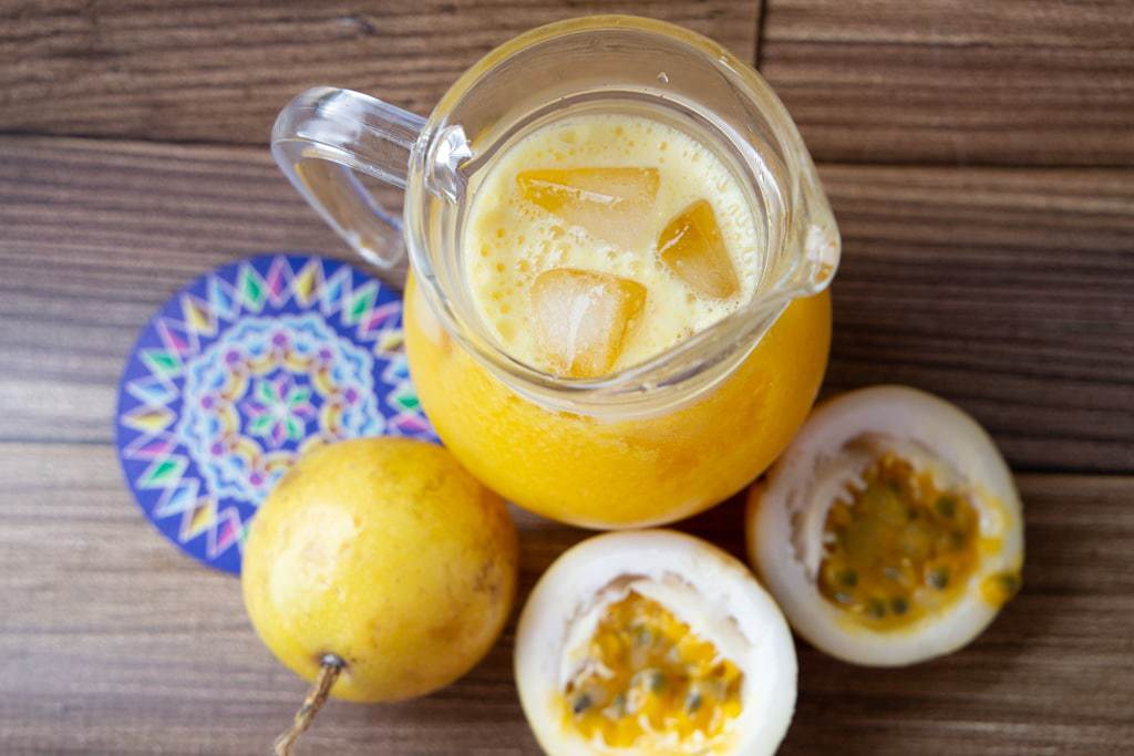 Aerial shot of a pitcher of passion fruit juice on a wooden table.
