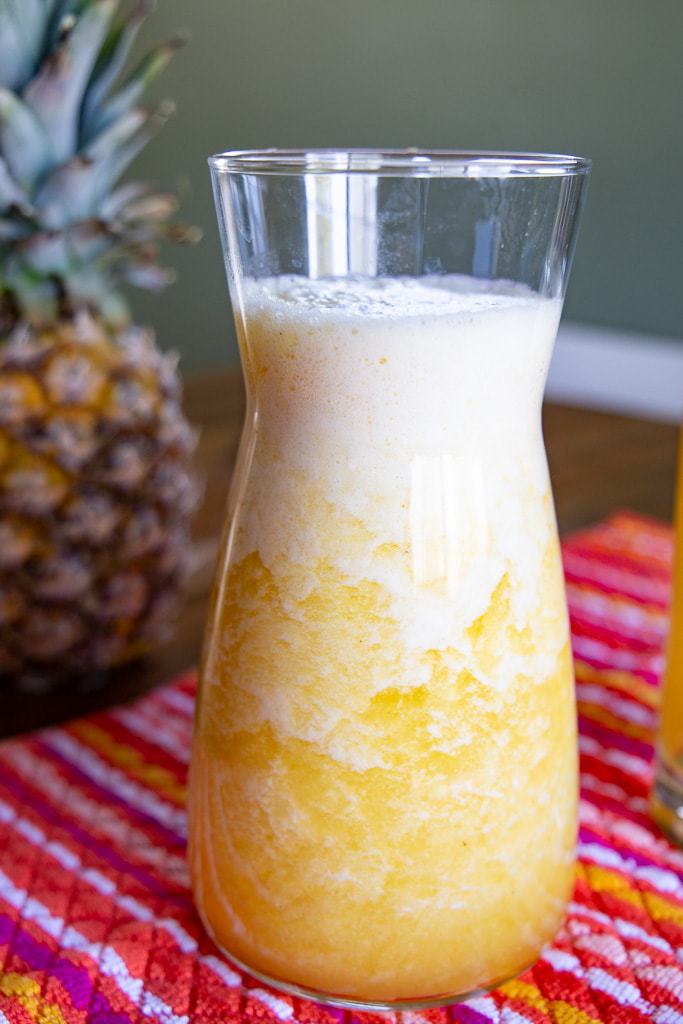 Carafe of fresh Costa Rican pineapple juice resting on a striped cloth.