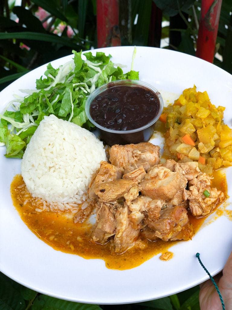 Large white plate with portions of white rice, chicken, picadillo, salad, and black beans.