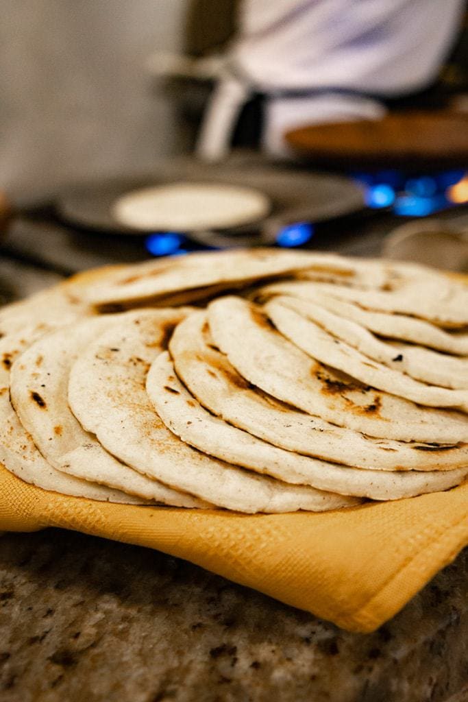 The tortillas laid out on top of each other on a dark wooden table.