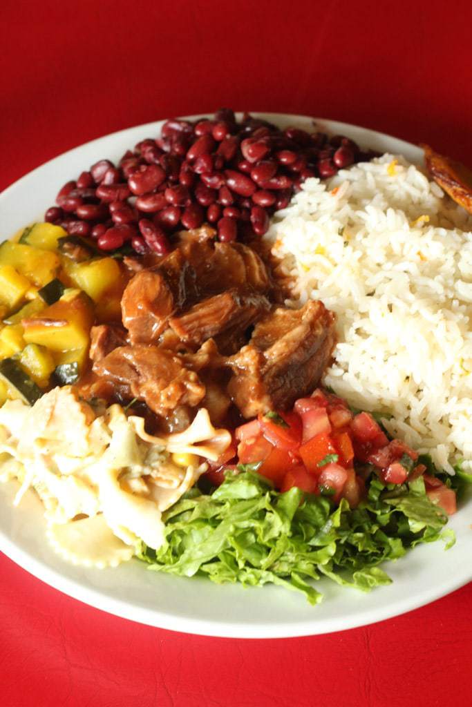 full plate of costa rican casado with red beans, rice, meat, salad and vegetables.