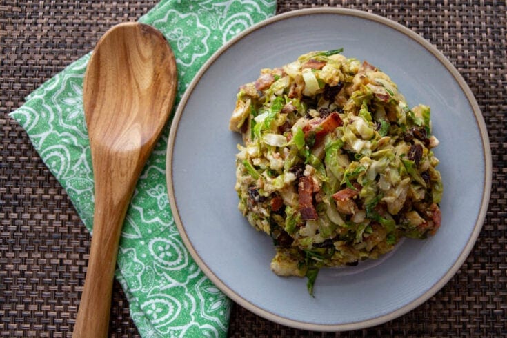 costa rican vegan roasted brussel sprout sald on plate with teal napkin and wooden spoon.