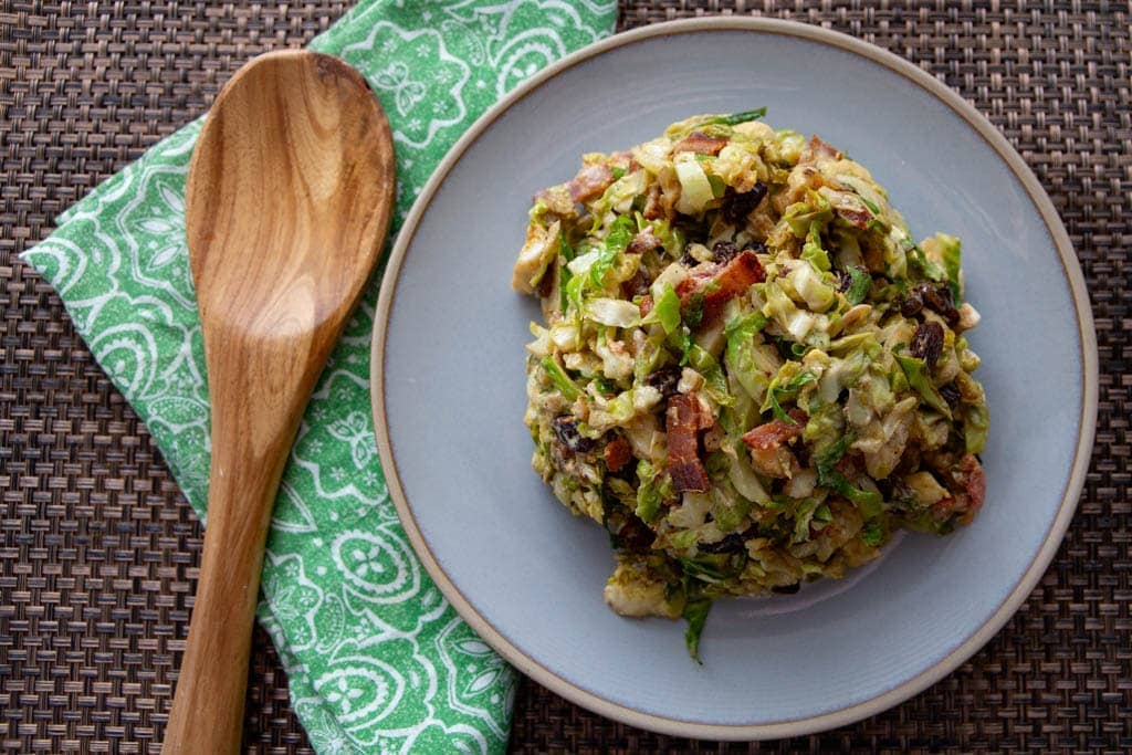 costa rican vegan roasted brussel sprout sald on plate with teal napkin and wooden spoon.