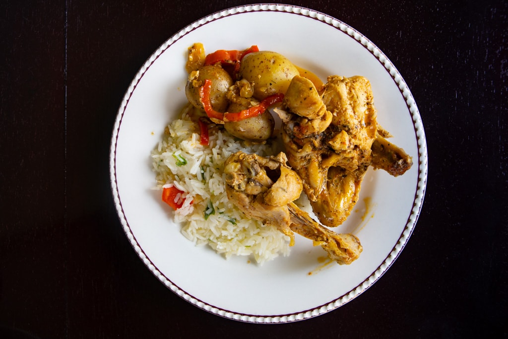 Costa Rican Chicken With Achiote on a white plate with a black background