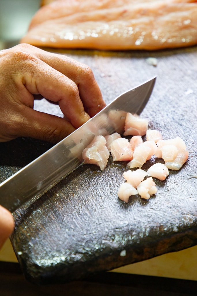 a chef knife, cutting up fish into cubes.